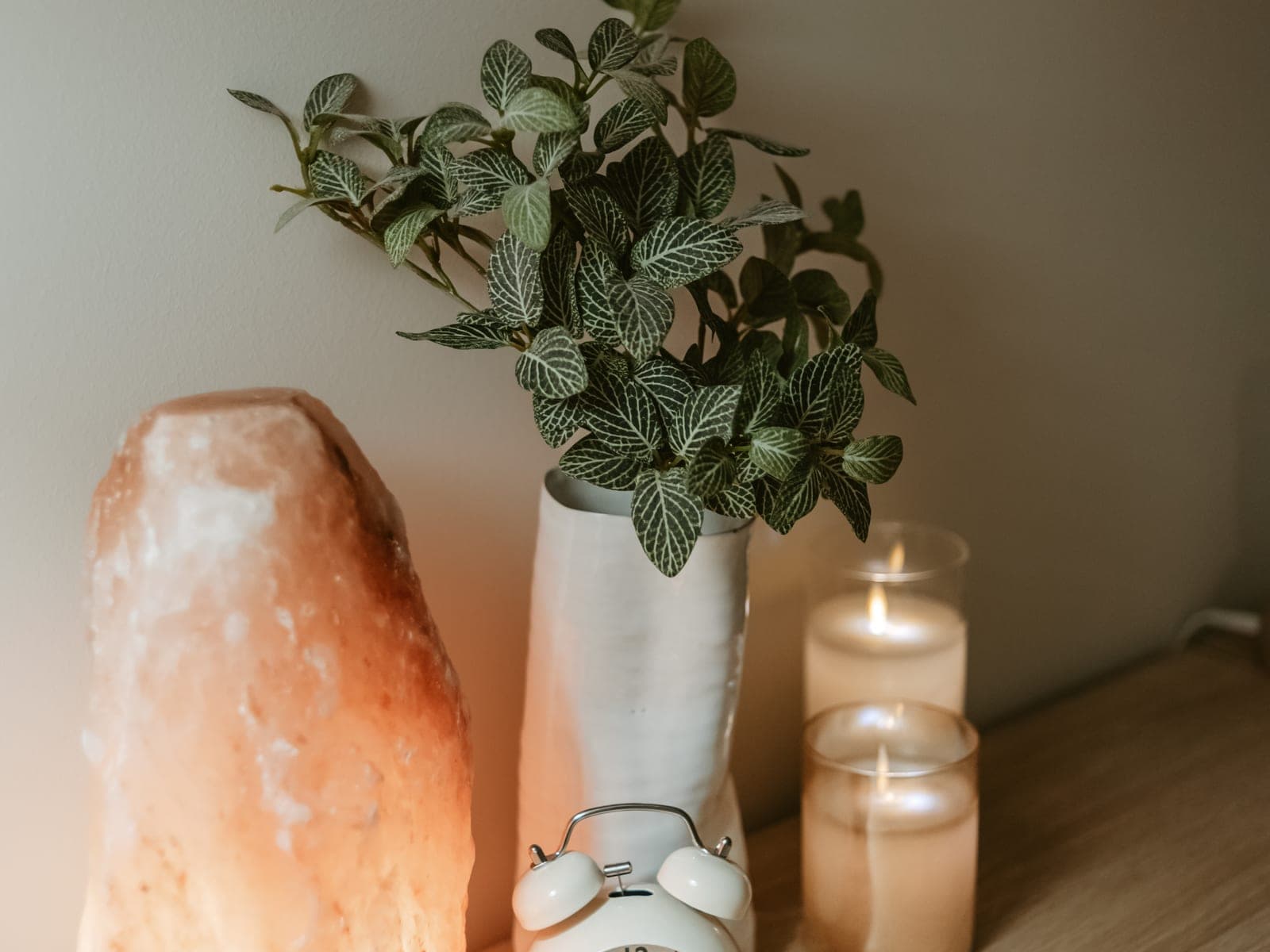 A lit salt lamp, a potted plant and burning candles on a shelf in the Nourish Skin Nashville treatment room