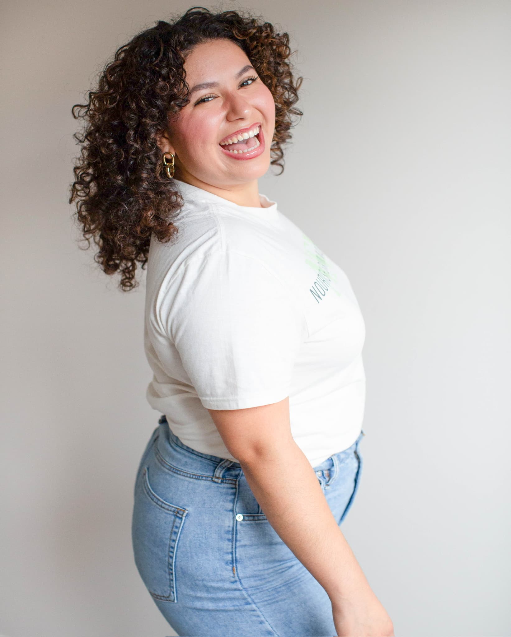 Roselyn Hernandez standing three-quarters away from the camera, looking back over her shoulder and laughing