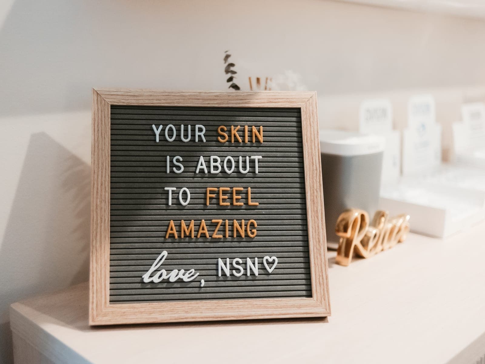 A letterboard on the studio counter reading “Your skin is about to feel amazing — love, NSN”