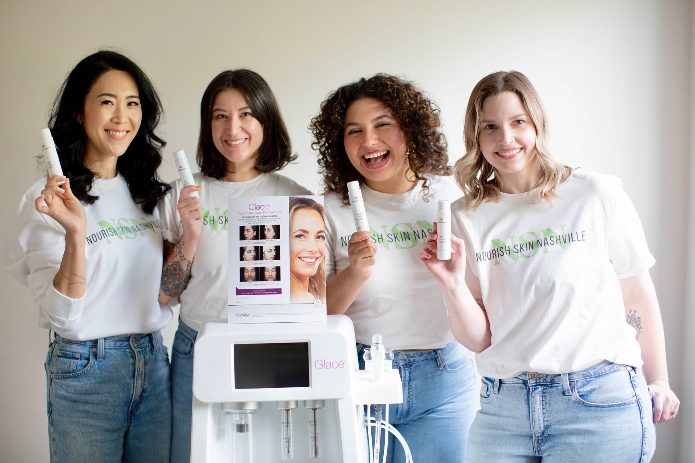 The four Nourish Skin Nashville estheticians in white T-shirts around the studio's Glacē device