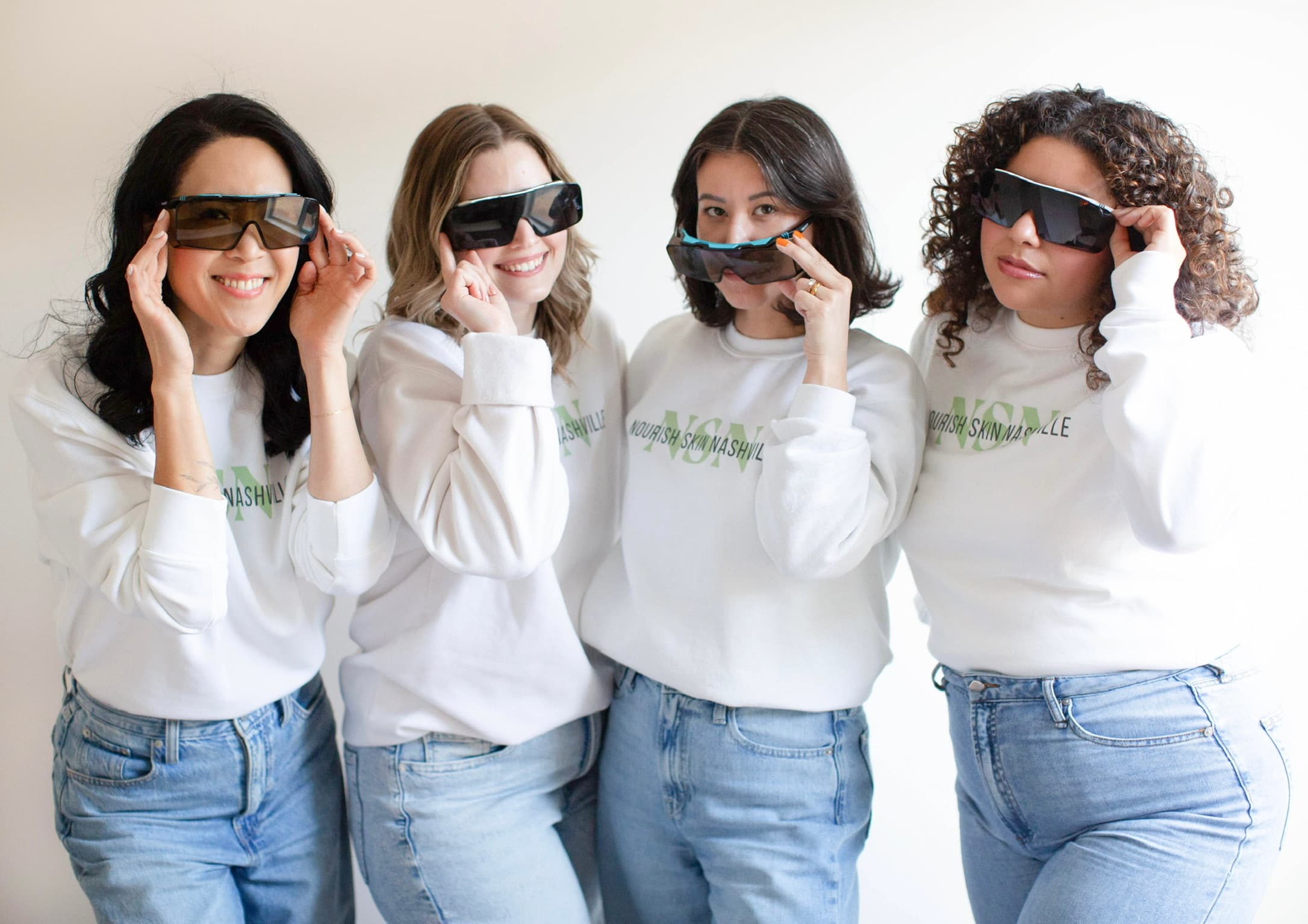 The four Nourish Skin Nashville estheticians in laser safety goggles, laughing